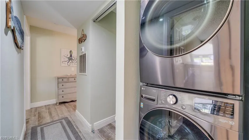 Laundry area featuring stacked washing machine and dryer and light wood-style flooring