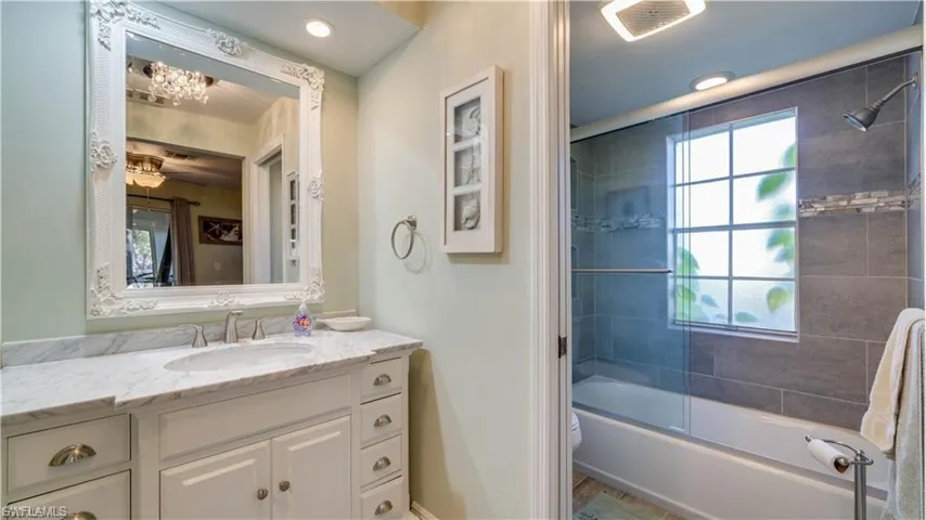 Bathroom with vanity and bath / shower combo with glass door