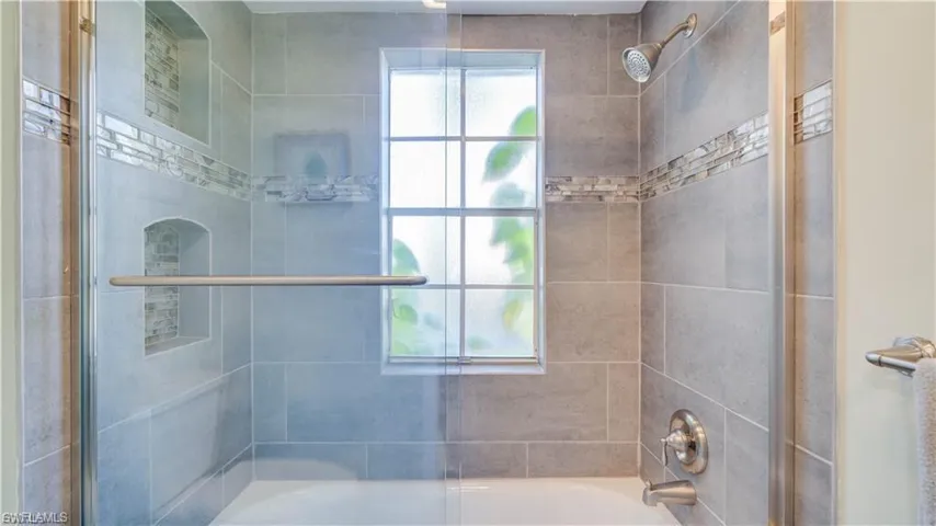 Bathroom with bath / shower combo with glass door