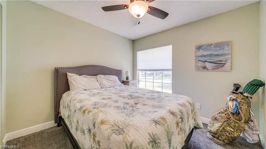 Bedroom with a textured ceiling, carpet floors, and a ceiling fan