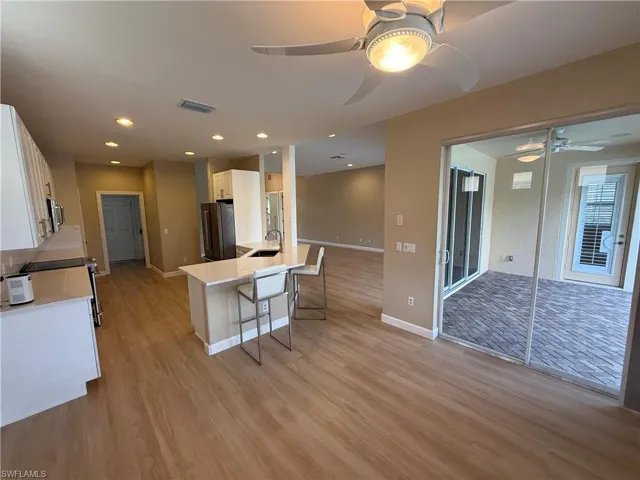 Kitchen with white cabinets, light stone counters, a kitchen bar, open floor plan, and appliances with stainless steel finishes