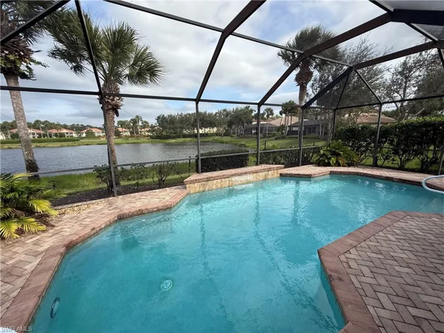 Outdoor pool with glass enclosure, a sunroom, a water view, and a residential view