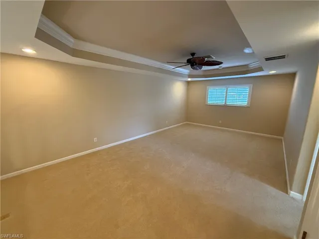 Carpeted spare room featuring a tray ceiling, recessed lighting, crown molding, and ceiling fan