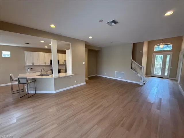 Unfurnished living room with healthy amount of natural light, recessed lighting, stairs, and light wood-style floors