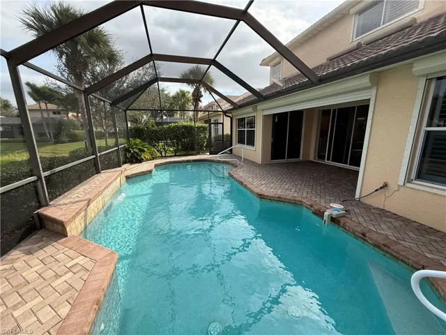Outdoor pool with a patio area, a sunroom, and glass enclosure