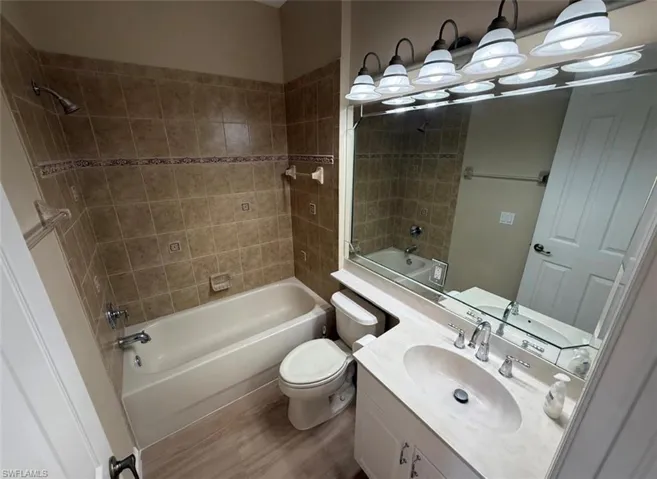 Bathroom featuring washtub / shower combination, vanity, and wood finished floors