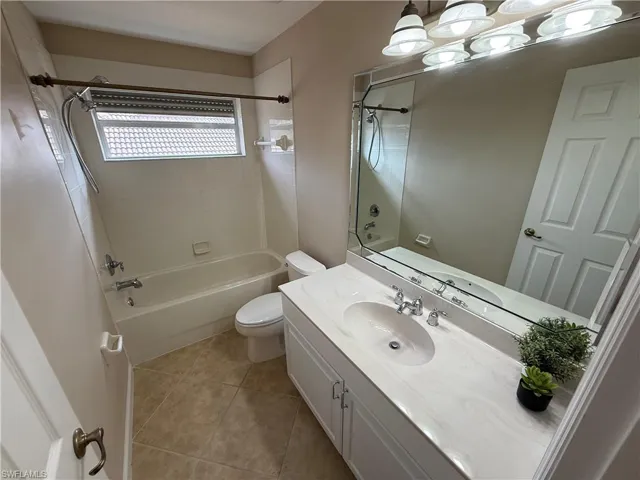 Full bathroom with washtub / shower combination, vanity, and light tile patterned flooring