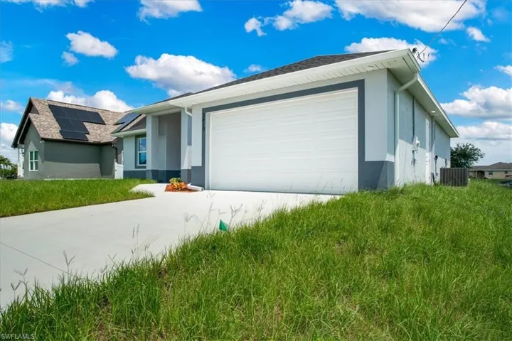 View of front of house with cooling unit, solar panels, and a garage