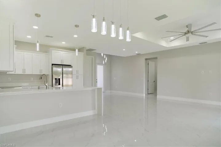 Kitchen with ceiling fan, decorative light fixtures, stainless steel fridge with ice dispenser, and white cabinets