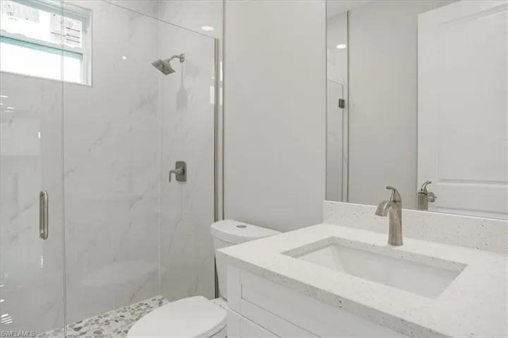 Bathroom featuring toilet, a shower with door, and vanity