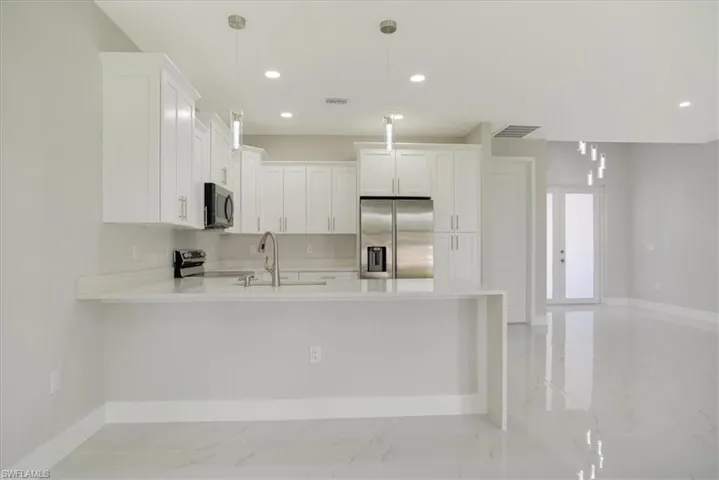 Kitchen featuring pendant lighting, sink, appliances with stainless steel finishes, and white cabinets