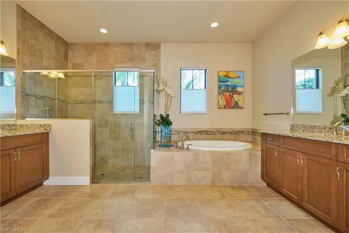 Bathroom featuring vanity, shower with separate bathtub, and a wealth of natural light