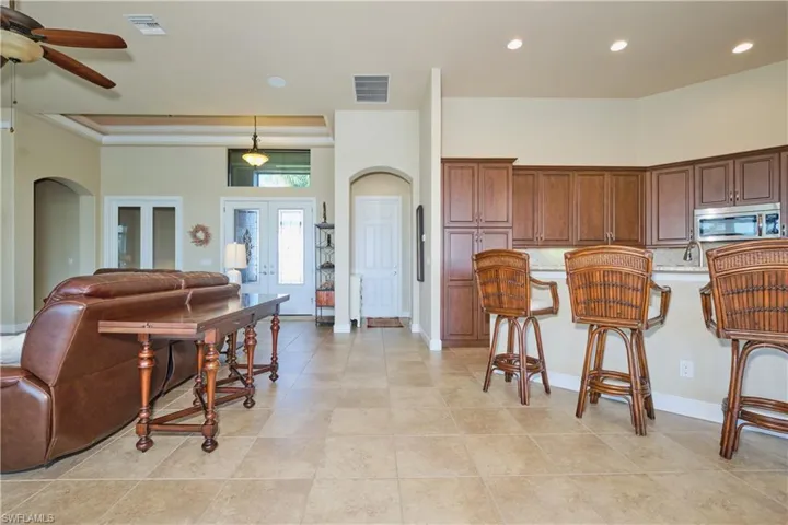 Kitchen with ceiling fan, light tile patterned floors, french doors, decorative light fixtures, and a kitchen breakfast bar