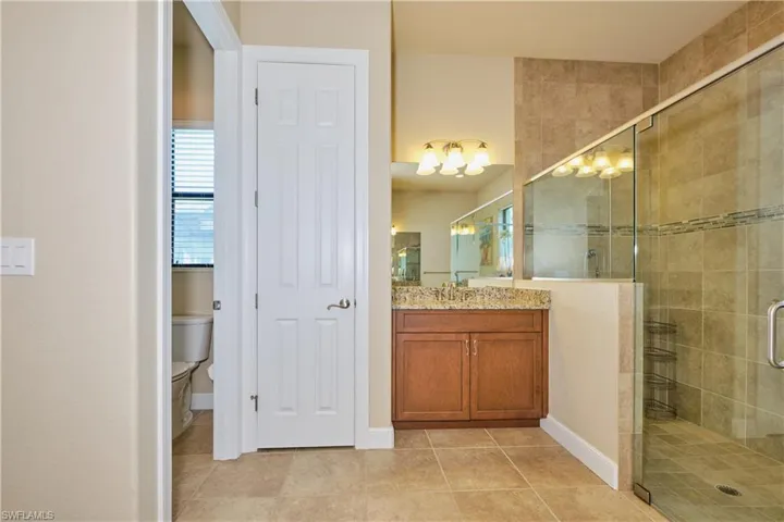 Bathroom with a shower with door, toilet, vanity, and tile patterned floors