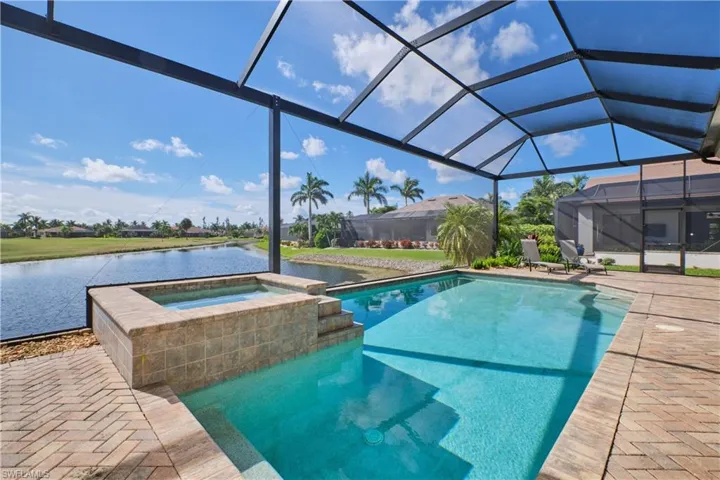 View of pool featuring a lanai, a patio, a water view, and an in ground hot tub