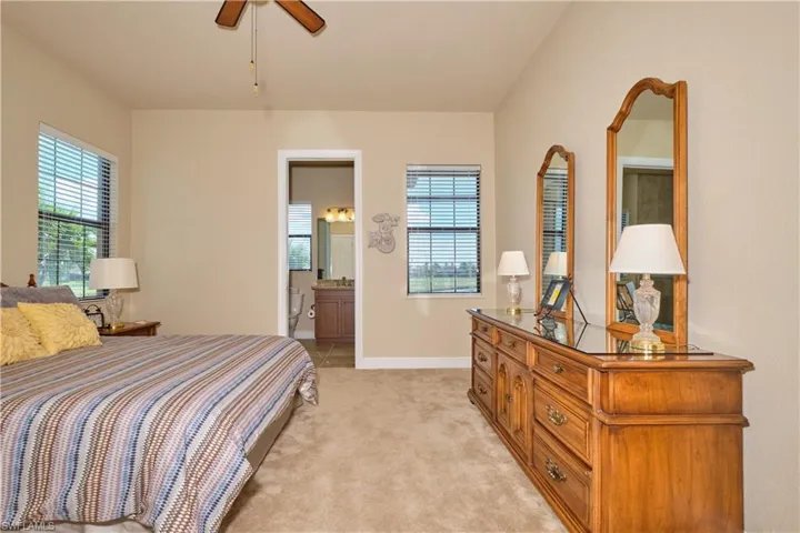 Carpeted bedroom featuring ceiling fan and ensuite bathroom