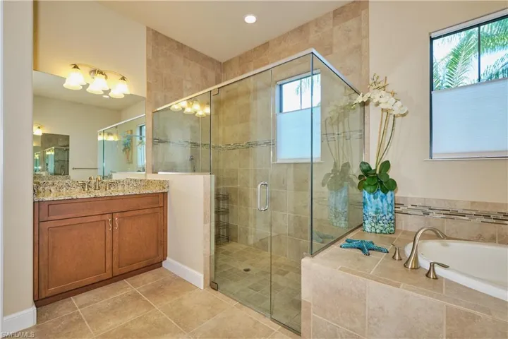 Bathroom featuring tile patterned floors, vanity, and separate shower and tub