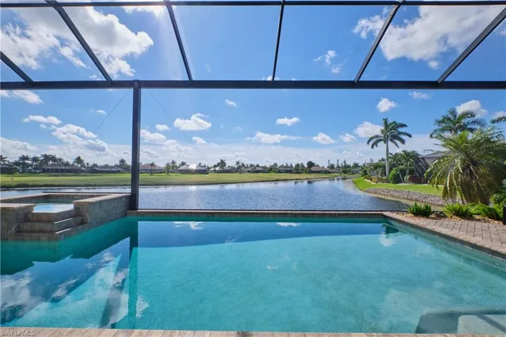 View of swimming pool featuring a water view, an in ground hot tub, and glass enclosure
