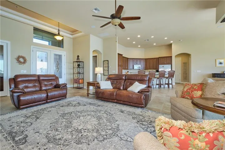 Living room with ornamental molding, a high ceiling, ceiling fan, and light tile patterned flooring