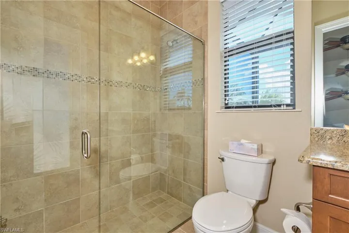 Bathroom with walk in shower, vanity, toilet, and ceiling fan