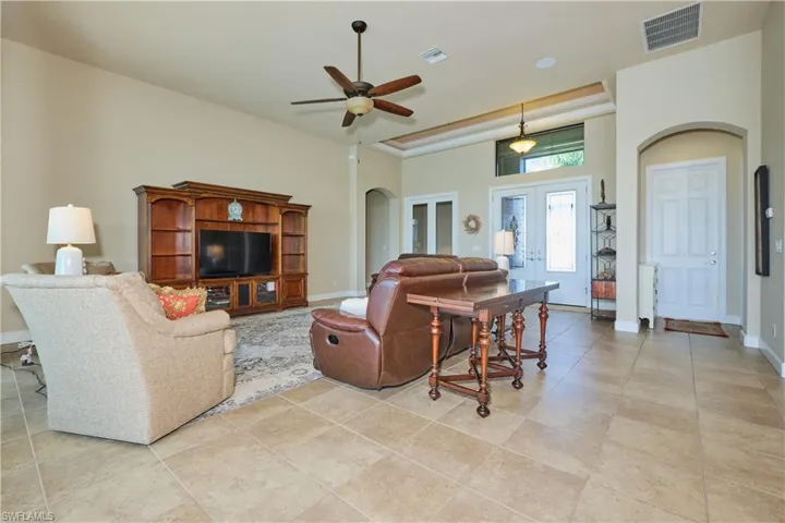 Tiled living room featuring ceiling fan and french doors