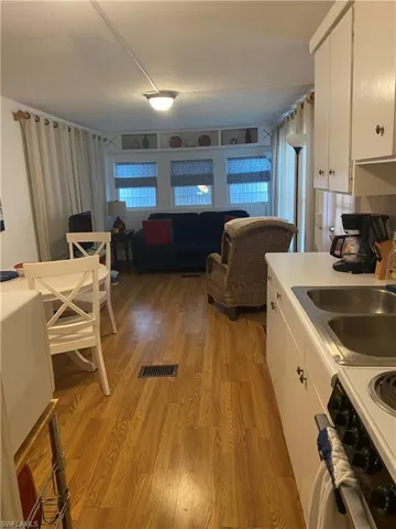 Kitchen featuring light laminate floors, range, a healthy amount of sunlight, and white cabinets