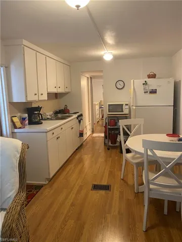 Kitchen featuring laminate floors, white appliances, and white cabinets