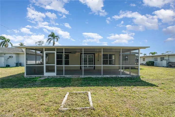 Back of property with a lawn and a sunroom