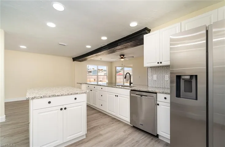 Kitchen featuring white cabinetry, appliances with stainless steel finishes, light stone counters, recessed lighting, and light wood-style floors
