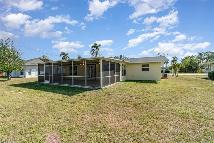 Back of house with a yard, stucco siding, and a sunroom