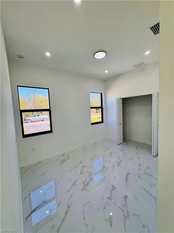 Unfurnished bedroom with marble finish floors and recessed lighting