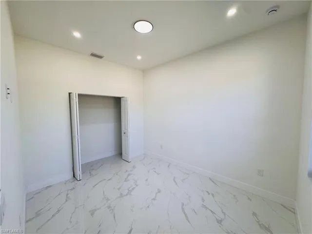 Unfurnished bedroom with light marble finish floors, recessed lighting, and a closet
