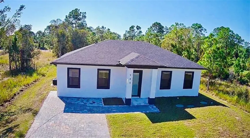 View of front of house featuring a front lawn, stucco siding, and a shingled roof