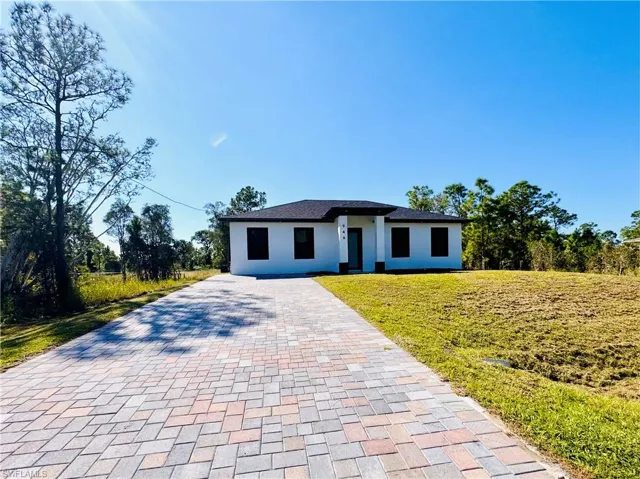 Prairie-style house with a front yard, decorative driveway, and stucco siding