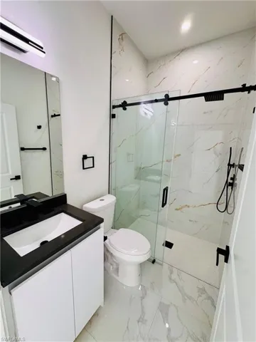 Bathroom with vanity, light marble finish flooring, a wall mounted AC, and a marble finish shower