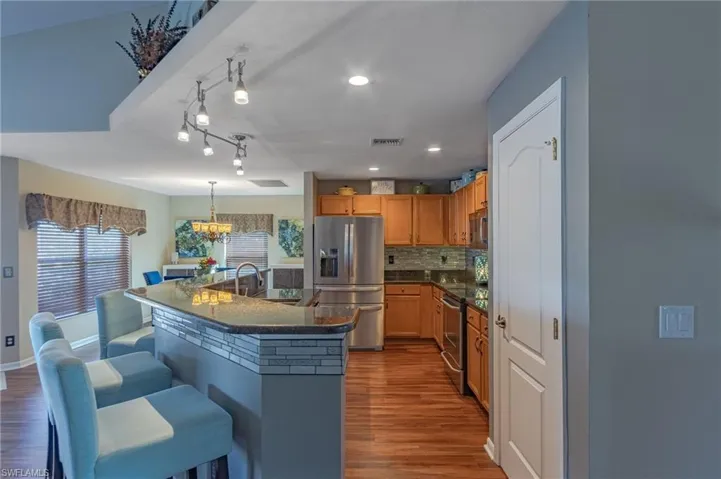 Kitchen featuring decorative light fixtures, sink, a breakfast bar area, a kitchen island with sink, and stainless steel appliances