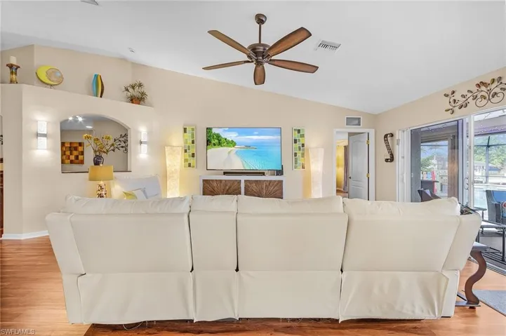 Living room with vaulted ceiling, ceiling fan, and light hardwood / wood-style flooring
