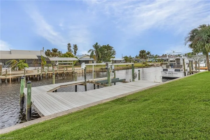 View of dock with a water view and a lawn