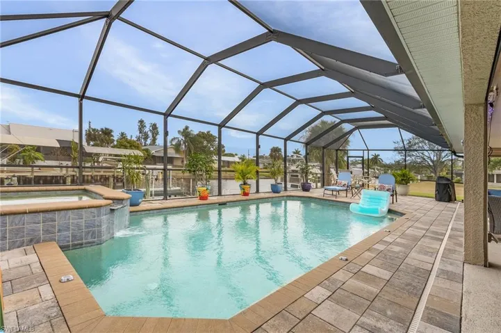 View of pool with an in ground hot tub, glass enclosure, and a patio area