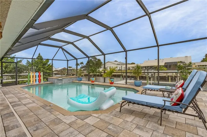 View of pool featuring an in ground hot tub, a water view, glass enclosure, and a patio