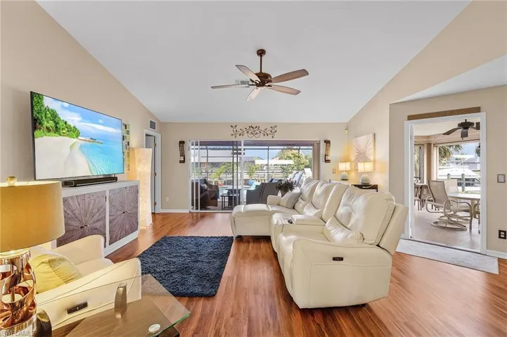Living room with vaulted ceiling, ceiling fan, and hardwood / wood-style floors
