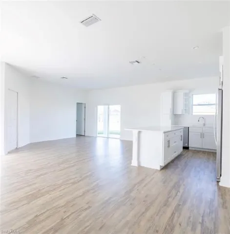 Kitchen featuring light hardwood / wood-style floors, white cabinets, a healthy amount of sunlight, and a kitchen island