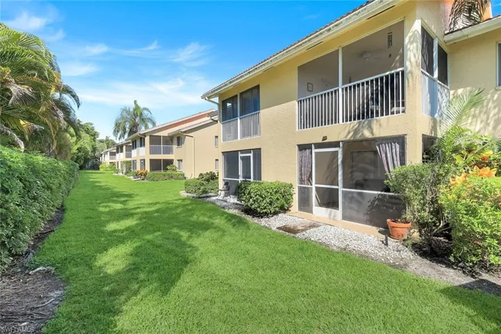 View of green lawn with a balcony and a sunroom