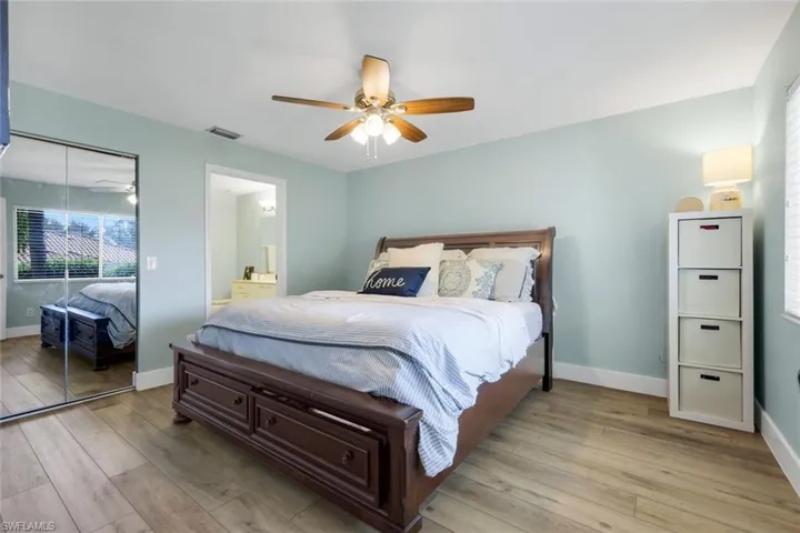 Bedroom with light wood-style floors, ceiling fan, connected bathroom, and a closet