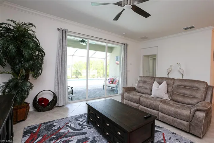 Tiled living room featuring ceiling fan and ornamental molding