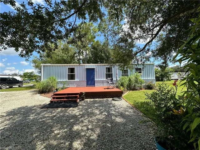 Back of house with board and batten siding, a deck, and a yard