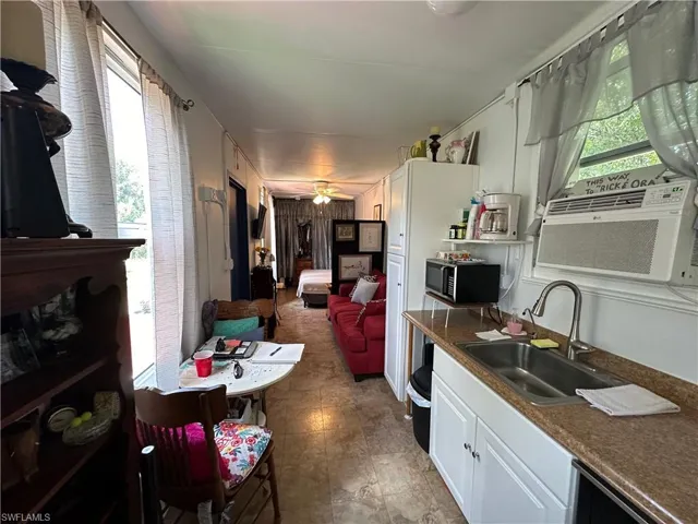 Kitchen featuring dark countertops, white cabinetry, stainless steel microwave, and cooling unit