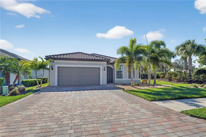 View of front of property featuring decorative driveway, a garage, stucco siding, and a front yard