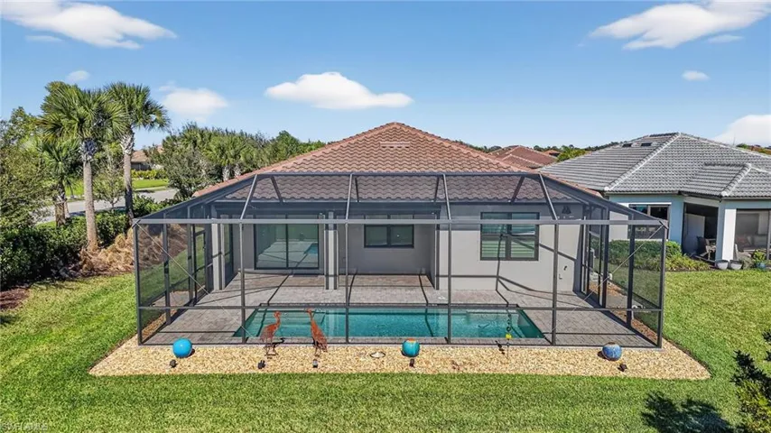 Rear view of property featuring a lawn, an outdoor pool, and glass enclosure