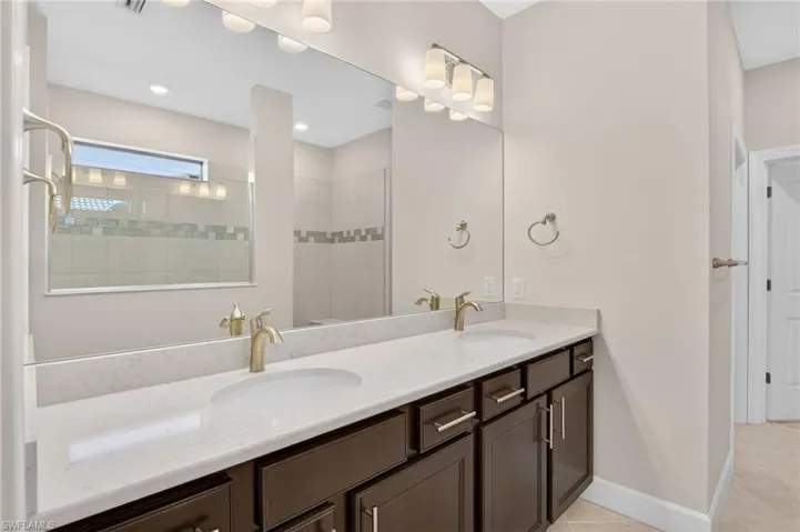 Full bathroom featuring a walk in shower, double vanity, and light tile patterned flooring